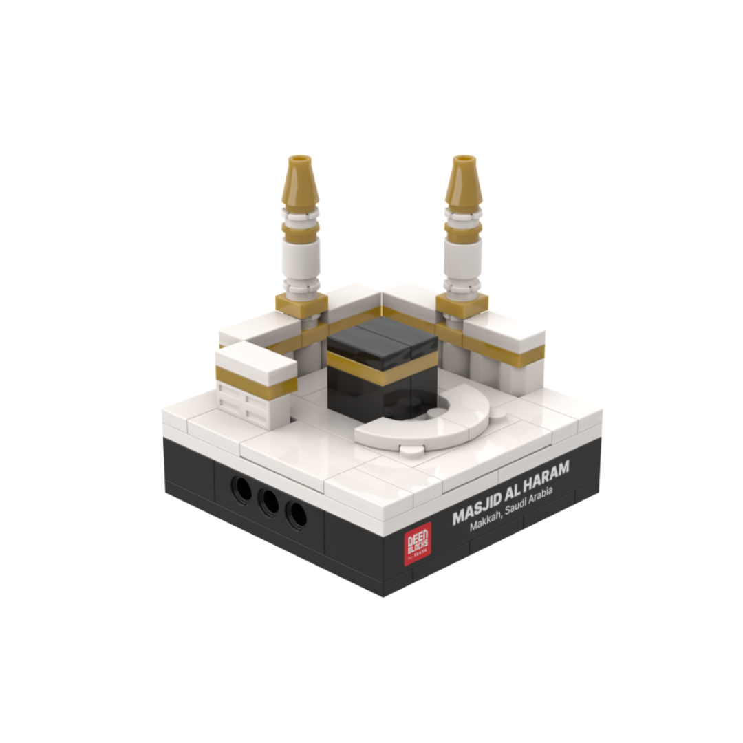 Masjid Al Haram mini building blocks set, a desk-size Islamic collectible shown at an angle on white, featuring the black Kaaba and its gold band, two gold-tipped minarets and white masjid walls, set on a black DEENBLOCKS nameplate base