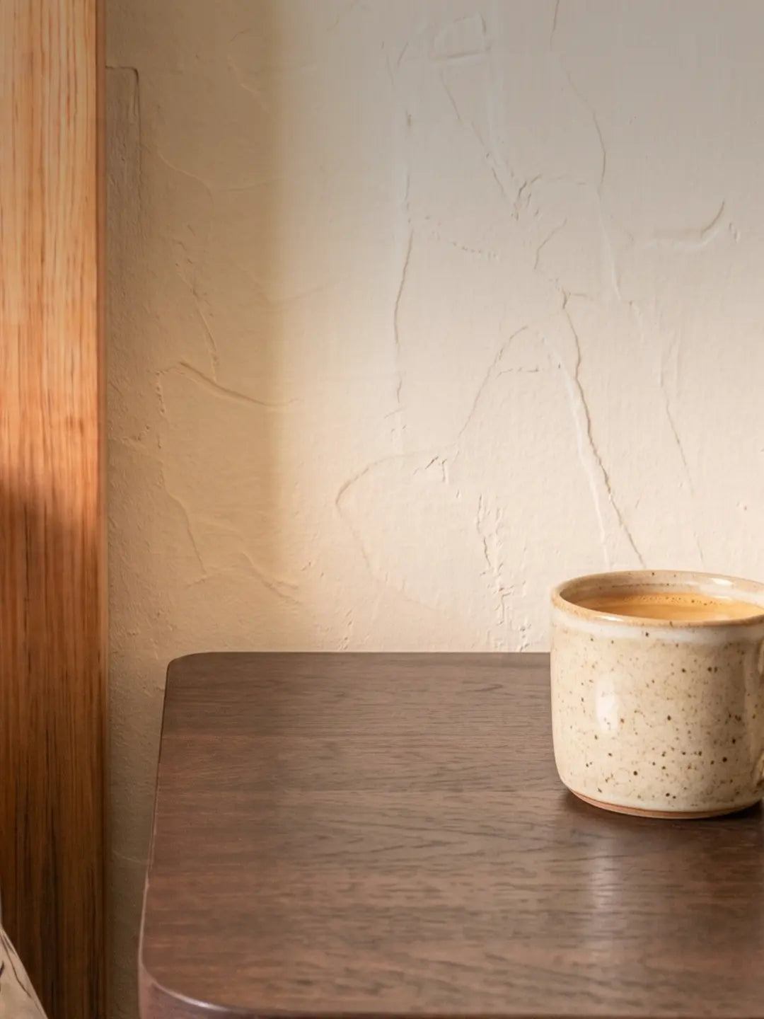 Dark wooden bedside table against a textured plaster wall with a phone at its edge, the bedside setting used to display a mini mosque building blocks model (mobile copy)